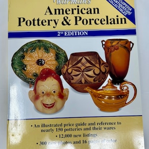 May include: Cover of a book titled "Warman's American Pottery & Porcelain, 2nd Edition". The cover features a colorful illustration of various pottery pieces, including a green and yellow plate, a brown and black pot, a gold teapot, and a whimsical ceramic figure.