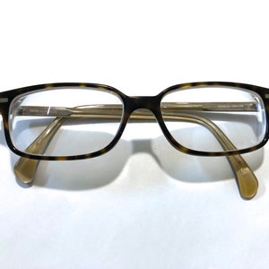 May include: Tortoise shell eyeglasses with gold metal arms. The arms are marked "Oliver Peoples OV5226U 4926-145 145".