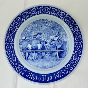 Puede incluir: Una taza de cerámica blanca con un asa negra y el texto "But First, Coffee" en negrita negra. La taza está llena de un líquido oscuro, probablemente café, y se encuentra sobre una superficie clara.