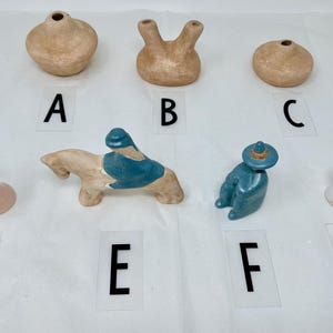 Puede incluir: Una colección de ocho figuritas de cerámica, que incluyen una mujer que sostiene un bebé, una persona que monta a caballo, una persona sentada y una mujer con un vestido blanco. También hay tres pequeños jarrones de cerámica.