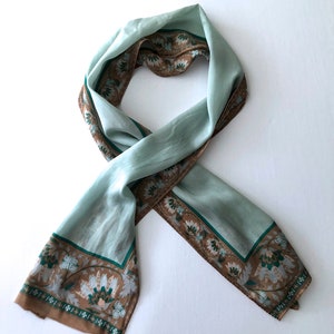 May include: A light blue silk scarf with a brown and green floral border.