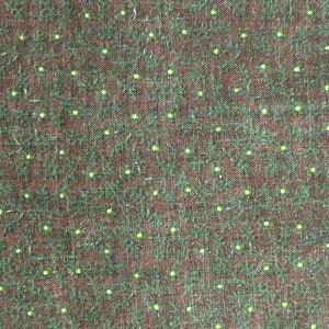 May include: Close-up of a fabric with a repeating pattern of small yellow dots and green floral shapes on a dark brown background. The fabric has a textured appearance.