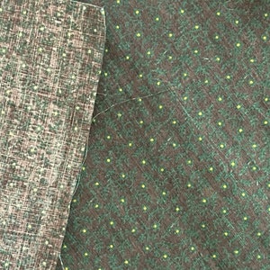 May include: Two pieces of fabric with different patterns. The left piece has a brown and white grid pattern. The right piece has a dark green background with small yellow dots and a leaf-like design. A white thread is visible.