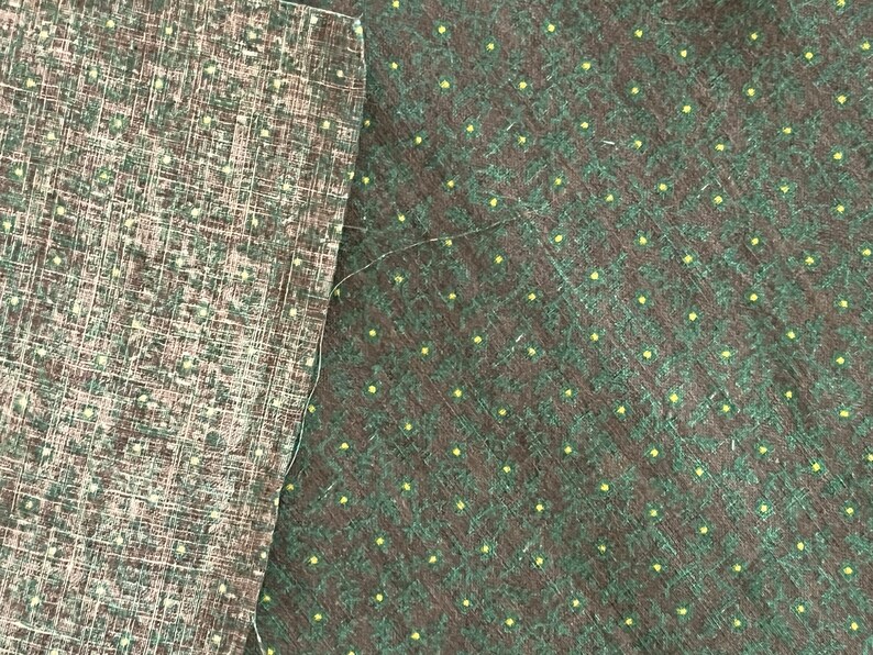 May include: Two pieces of fabric with different patterns. The left piece has a brown and white grid pattern. The right piece has a dark green background with small yellow dots and a leaf-like design. A white thread is visible.