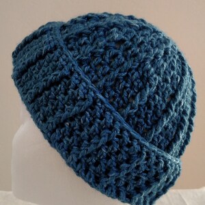 Puede incluir: Un gorro de punto azul con un ajuste holgado. El gorro está hecho con un patrón de punto texturizado.