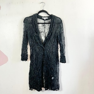 May include: A set of three ceramic mugs with a speckled, cream-colored glaze. Each mug features a different hand-painted design: a blue and green leaf, a yellow flower, and a red berry. The mugs have a simple, rounded shape.