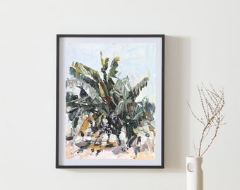 Op de afbeelding: Een ingelijst schilderij van een groene en bruine tropische plant met een witte achtergrond. Het schilderij is in een zwarte lijst en hangt aan een witte muur.