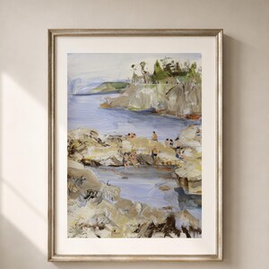 May include: Framed art print of a coastal scene. The painting depicts a rocky shoreline with figures, a body of water, and a distant landmass. The artwork features a palette of blues, greens, and earth tones, with visible brushstrokes. The frame is silver.