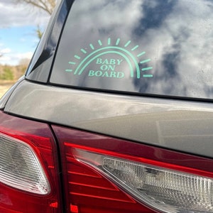 May include: A teal blue car sticker with a rainbow design and the text "BABY ON BOARD".