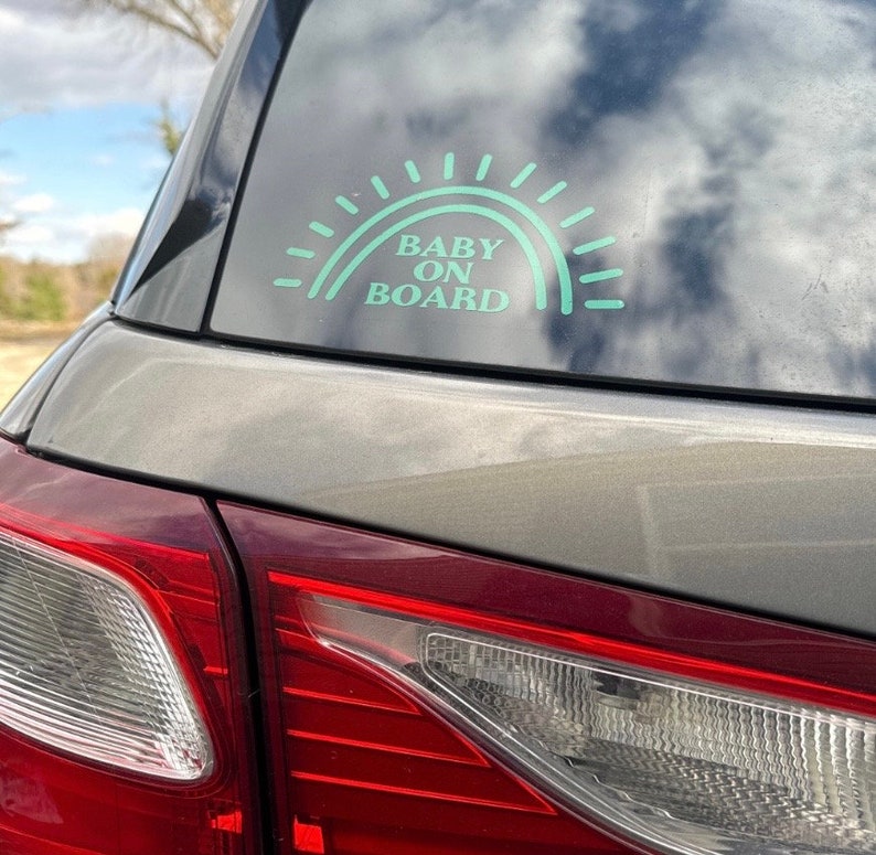 May include: A teal blue car sticker with a rainbow design and the text "BABY ON BOARD".