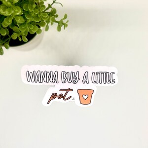May include: White sticker with the text "Wanna buy a little pot" and a small brown pot with a white heart on it.