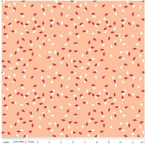 Op de afbeelding: Perzik kleurige stof met een verspreid patroon van kleine, blad-vormige ontwerpen in rood en wit. De stof heeft een herhalend patroon van de bladvormen. De afbeelding bevat een liniaal langs de onderrand, gemeten in inches.