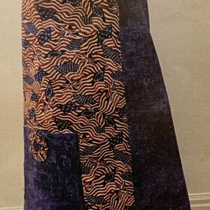 May include: A blue and red patterned apron with a red trim. The apron has a large pocket on the front and a tie at the neck.