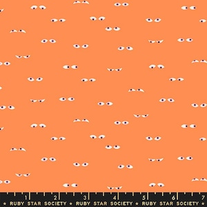 Könnte beinhalten: Ein pfirsichfarbener Stoff mit einem sich wiederholenden Muster aus weißen Augen. Der Stoff hat ein Lineal mit Zollmarkierungen und den aufgedruckten Text "RUBY STAR SOCIETY".