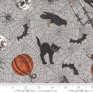 Può includere: Un tessuto grigio con una stampa di Halloween nera e arancione. La stampa presenta pipistrelli, ragni, gatti, zucche, teschi e corvi. Il tessuto è ricoperto da un motivo a ragnatela.
