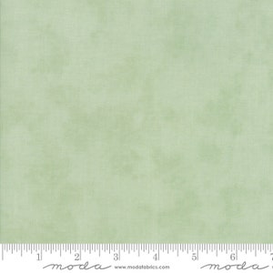 Op de afbeelding: Een effen groene stof met een subtiele, gemarmerde textuur. De stof is lichtgroen, vergelijkbaar met de kleur van een lenteblad.