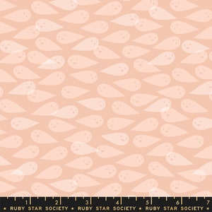 Op de afbeelding: Een perzikkleurige stof met een herhalend patroon van witte, spookachtige vormen met glimlachende gezichten.