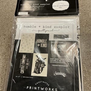 May include: A black and white Humble + Kind sampler quilt panel, packaged in clear plastic. The panel features text and graphics, including the words "Humble + Kind" and "American Cattle Company." The panel measures 36 x 54 inches.