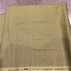 May include: A piece of olive green cotton fabric featuring a repeating geometric pattern of small black diamonds with centered lines. The selvage edge displays the text: The Treehouse Club by Sweetwater for moda, modafabrics.com, 100% cotton Stock #5634.