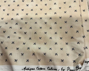 May include: A light beige cotton fabric featuring a repeating pattern of small, dark blue floral sprigs. The white selvage edge at the bottom displays the printed text, Antique Cotton Calicos by Pam Buda, in a black cursive and serif font style.