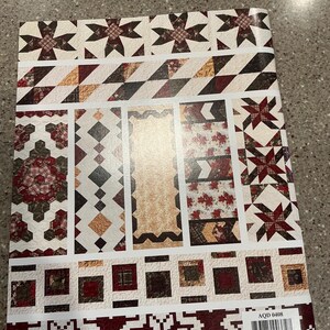May include: A quilt pattern book featuring various quilt block designs. The cover displays a patchwork of geometric patterns in shades of red, brown, beige, and white. The designs include stars, diamonds, squares, and floral prints. The book has the text "AQD 0408".