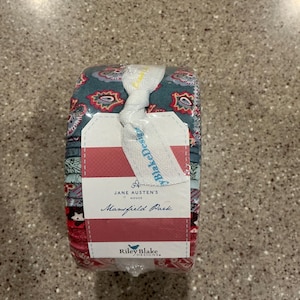 May include: A fabric jelly roll bundle featuring various patterned strips in shades of teal, red, and white. A white paper band wraps around the center, printed with the text Jane Austen's House Mansfield Park and the Riley Blake Designs logo.