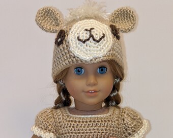 May include: A crocheted llama costume for an 18-inch doll, featuring a brown and white llama hat with ears, a brown dress with a flower trim, and white leggings.