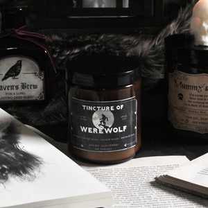 May include: Three glass jars with labels reading "Raven's Brew", "Tincture of Werewolf", and "Mummy's Curse". The jars are filled with candles and are surrounded by books and a skull.