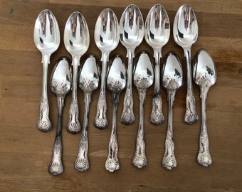 May include: A set of 10 silver spoons with ornate handles. The spoons are arranged in two rows, with the handles facing up. The spoons are all the same size and shape, and they have a polished finish.