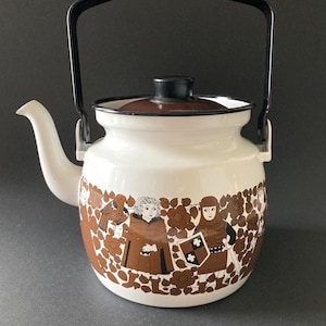 Puede incluir: Tetera de esmalte blanco con asa y tapa negras. La tetera presenta un diseño marrón y blanco de figuras y motivos florales alrededor de la base. El pico es blanco y el asa es negra.