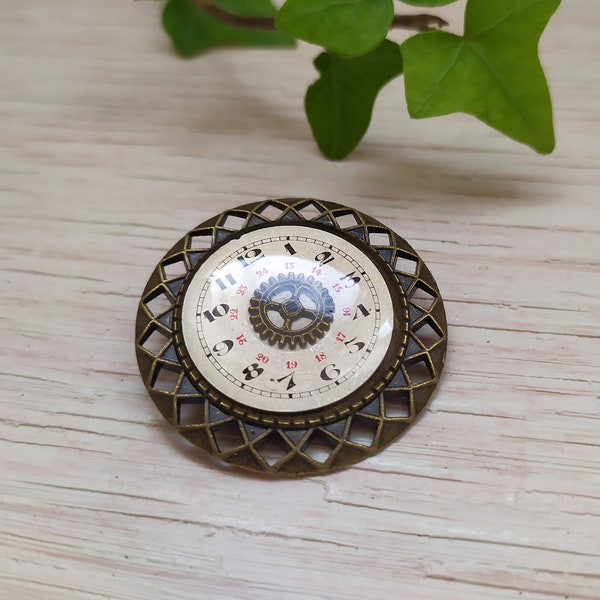 Broche ronde couleur bronze avec cadrant de montre et bords géométriques
