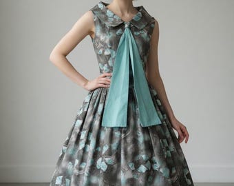 Precioso vestido de día original de los años 50 con cuello alto y cintura baja, estampado floral novedoso.