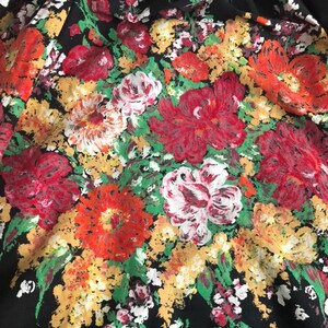 May include: A black fabric featuring a dense, painterly floral print. The pattern consists of large, textured blossoms in shades of vibrant red, deep crimson, soft white, and golden yellow, interspersed with bright green foliage throughout.