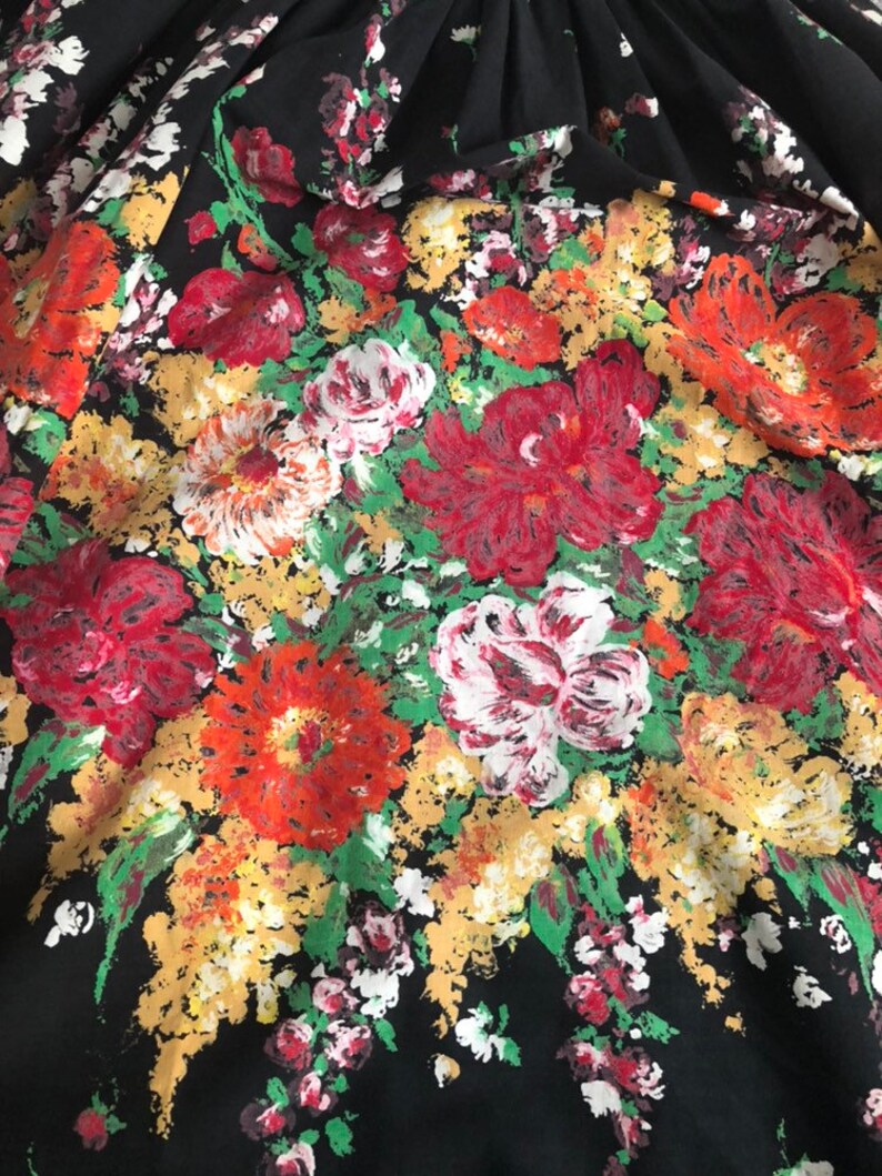 May include: A black fabric featuring a dense, painterly floral print. The pattern consists of large, textured blossoms in shades of vibrant red, deep crimson, soft white, and golden yellow, interspersed with bright green foliage throughout.