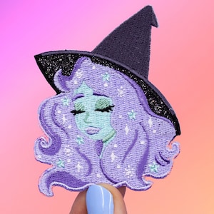 Puede incluir: Parche de bruja bordado en morado y verde con un sombrero de bruja negro y detalles de purpurina.