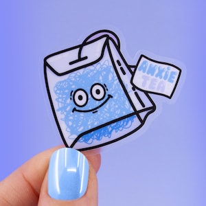Peut inclure: Un autocollant transparent avec un sachet de thé dessiné en bleu et blanc avec un visage souriant. Le sachet de thé a une étiquette qui dit "Anxie Tea".