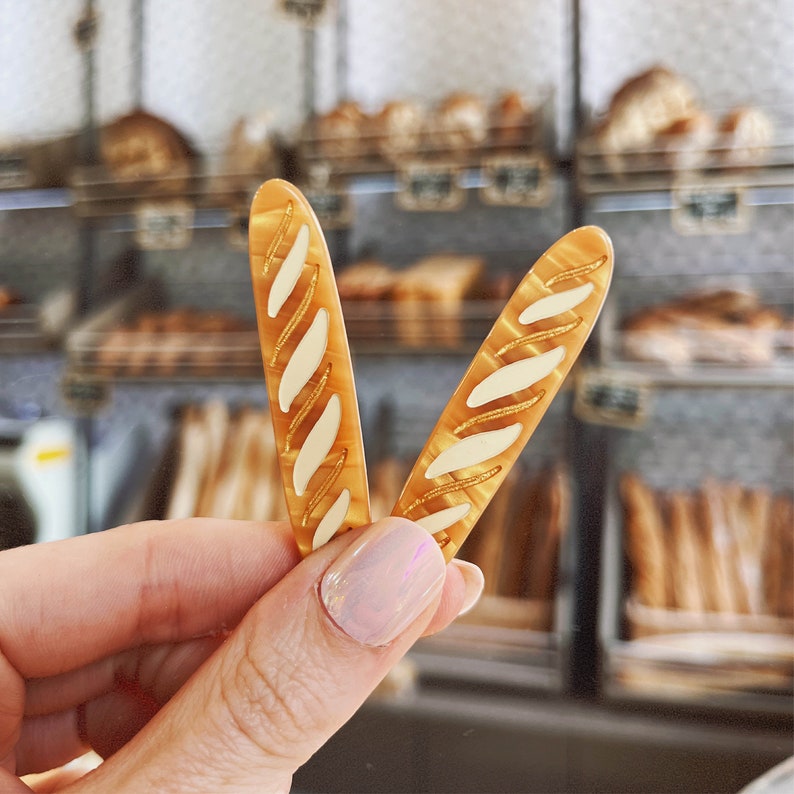 May include: Two brown and white patterned hair clips shaped like baguettes.