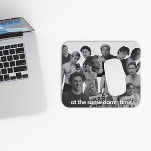 May include: A rectangular mouse pad featuring a black and white collage of multiple portraits of a young man in various poses, including shirtless and wearing a jersey, with the white text "at the same damn time" printed at the bottom.