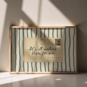 May include: A framed print with a vintage postcard design. The postcard, with a stamp and postmark, reads "It's all waiting there for you." The background has a striped pattern in white and green, within a wooden frame.