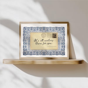 May include: A framed print featuring a vintage postcard design. The postcard has a cream-colored background with the text "It's all waiting there for you." It is surrounded by a blue and white floral border and a wooden frame.