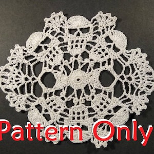 Puede incluir: Doily de crochet blanco con un diseño de calavera. El doily está hecho con puntadas delicadas y tiene un aspecto de encaje. "Pattern Only" está escrito en letras rojas en la parte inferior de la imagen.