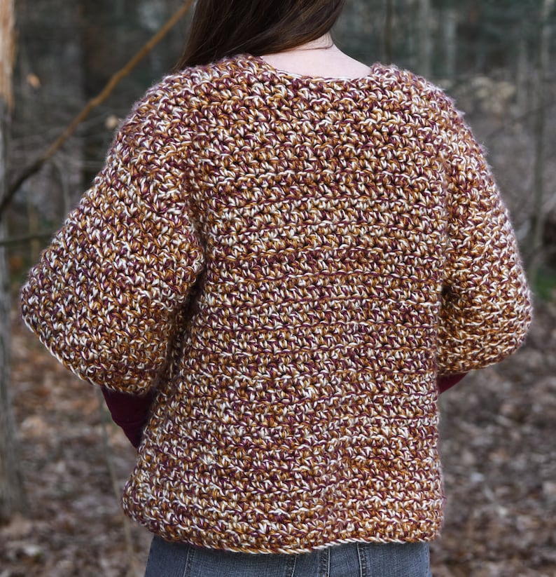 May include: A brown, white, and burgundy crocheted cardigan with a v-neck and long sleeves.