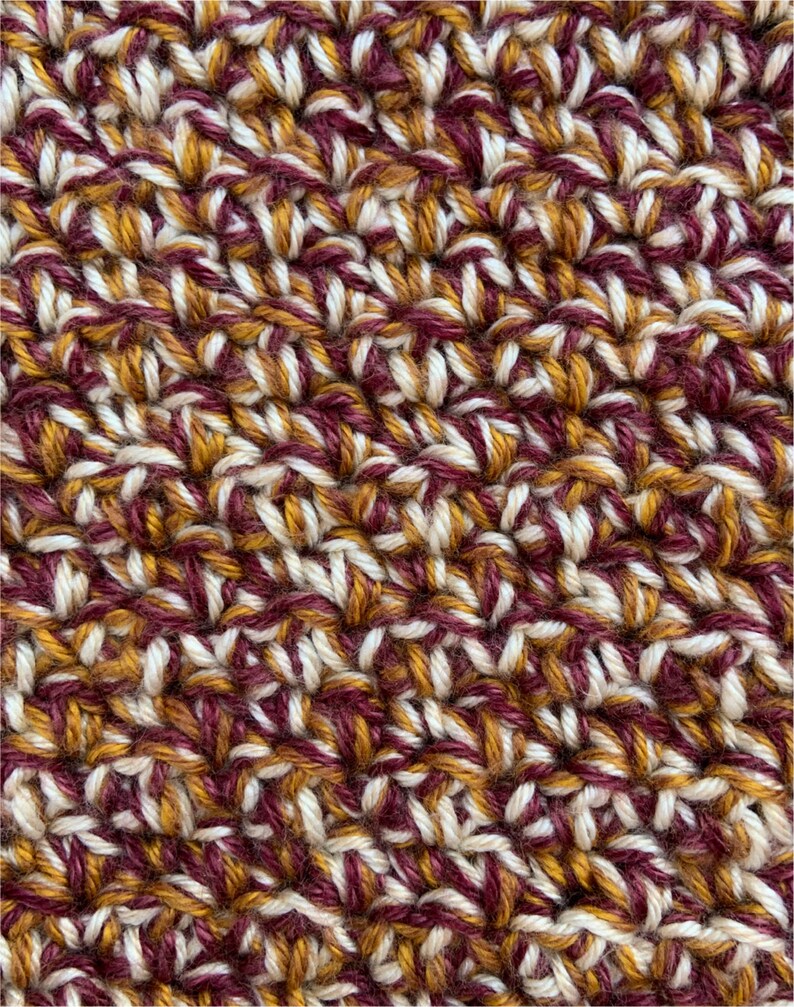 May include: Close-up of a crocheted fabric with a textured pattern in shades of burgundy, white, and gold.