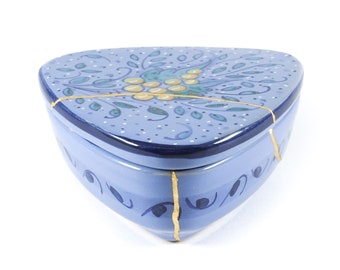 Peut inclure: Une boîte triangulaire en céramique bleue et dorée avec un motif floral. La boîte est fissurée et présente des accents dorés.