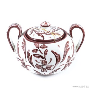 May include: White ceramic sugar bowl with a lid, decorated with brown floral patterns. The lid has a crack with gold accents.