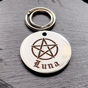 May include: Silver pet tag with a pentagram design and the name "Luna" engraved in a gothic font.