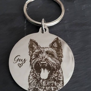 May include: A silver keychain with a round tag featuring a black and white engraved image of a dog with the name "Gus" and a heart.