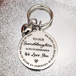 May include: Silver keychain with a heart charm and a round tag that reads "To our Granddaughter Always Remember We Love You Believe in Yourself as Much as We Believe in You. We Hope You Believe in You."