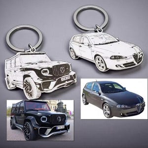 以下が含まれることがあります： シルバーのキーリングが付いた、車をテーマにした2つのキーホルダー。1つのキーホルダーはSUVの白黒スケッチ、もう1つはハッチバックです。下には同じ車のモデルの写真があります。