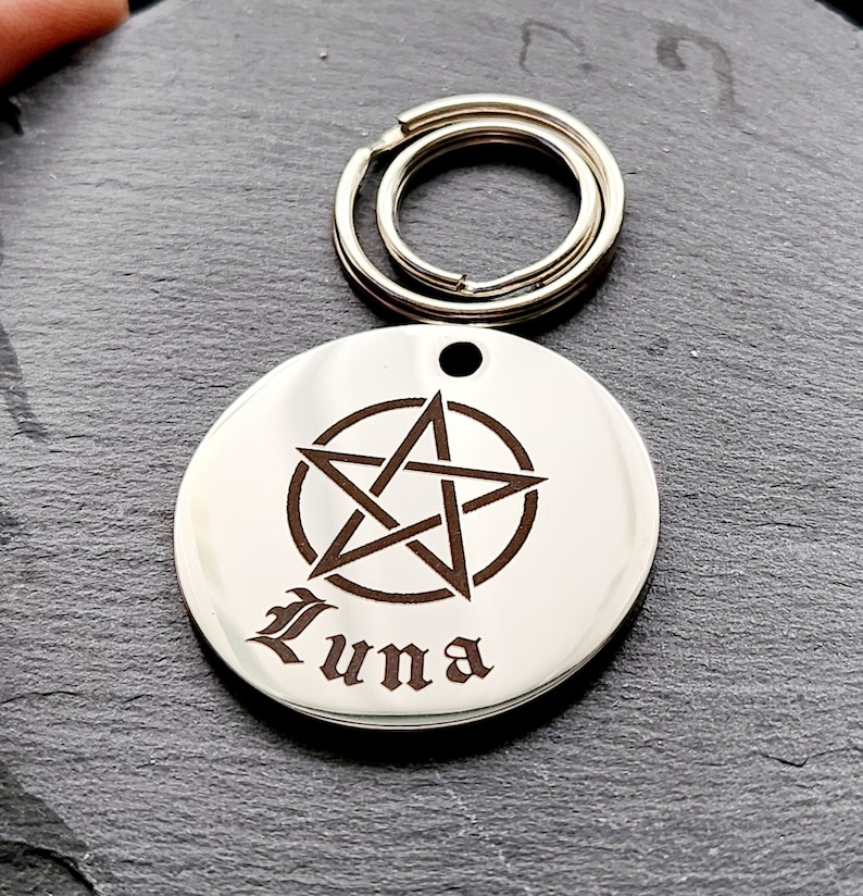 May include: Silver round keychain with a pentagram engraved on it. The name "Luna" is engraved below the pentagram.